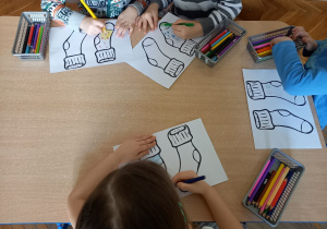 Dzieci kolorują kolorowankę przedstawiającą skarpetki.